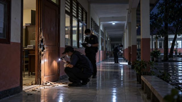 Petugas memeriksa pintu ruang sekolah yang rusak di koridor kosong pada malam hari